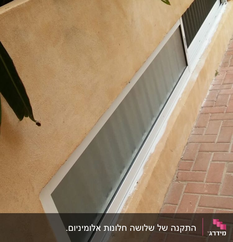 חלון אלומיניום עם מסגרת לבנה בקיר חיצוני